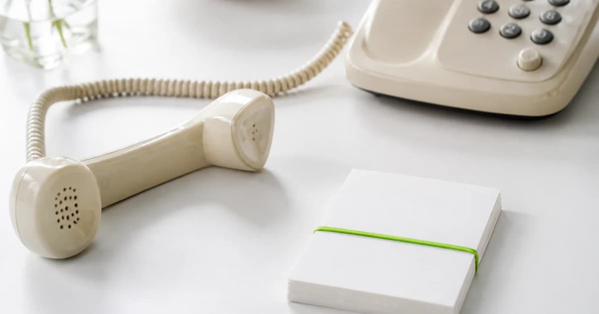 Cream landline off the hook next to lime-banded note cards